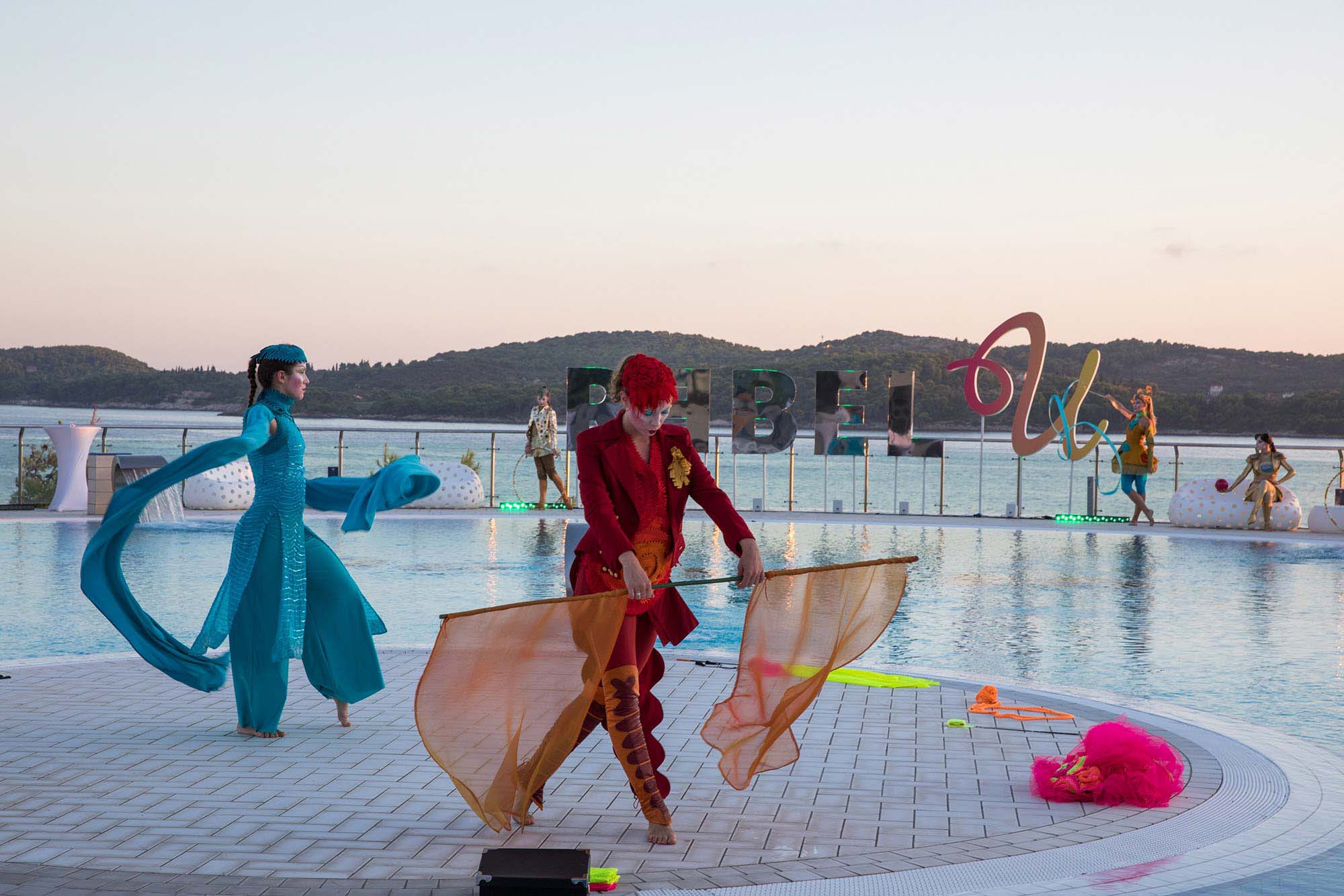 Experiential Events – Vibrant costumed acrobat entertainers around the exclusive hotel pool area overlooking Adriatic sea